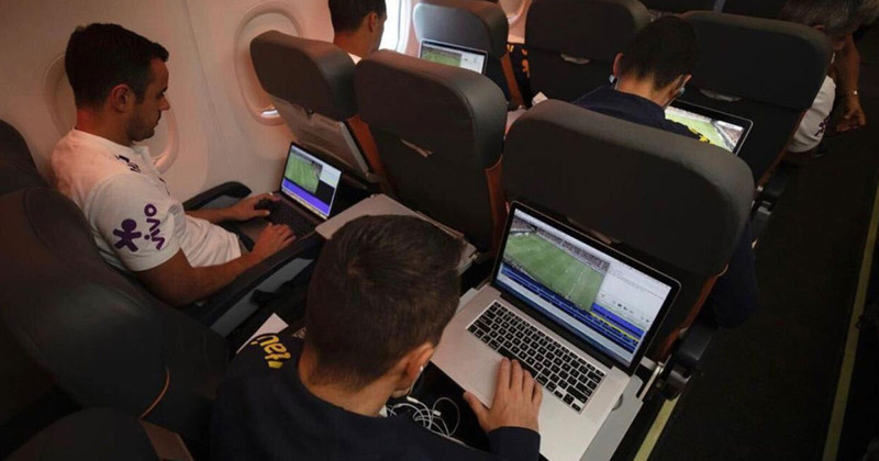 Jogadores brasileiros vendo Hudl em laptops no avião.