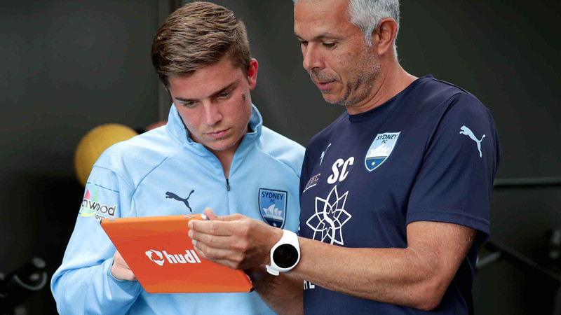 Treinador mostrando análises de jogadores do Sydney FC em um tablet Hudl