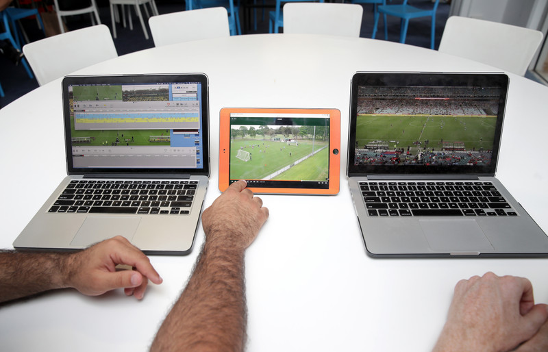 Dois homens assistindo a vídeos de partidas de futebol em laptops e um tablet